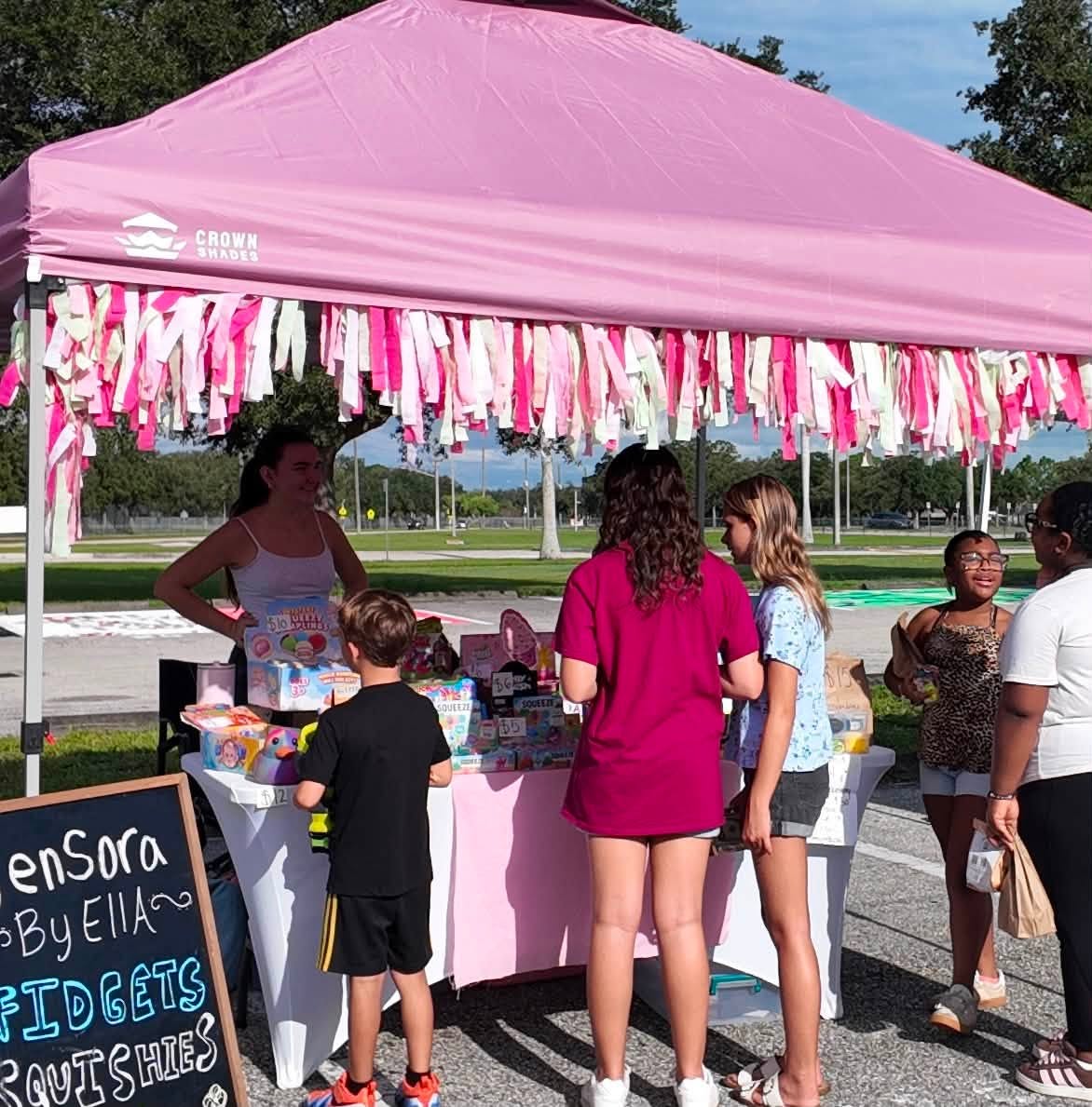 Kids browsing a bright pink tent full of fidgets and squishies