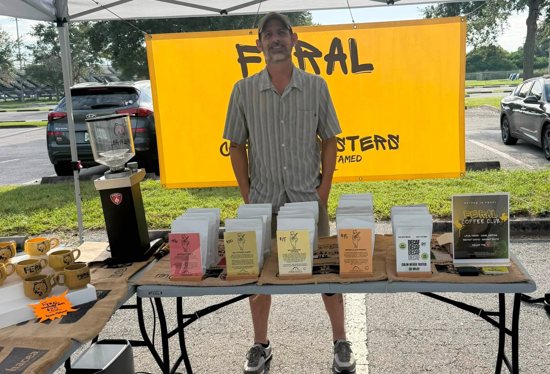 A local coffee roaster standing behind a table of freshly roasted bags of beans