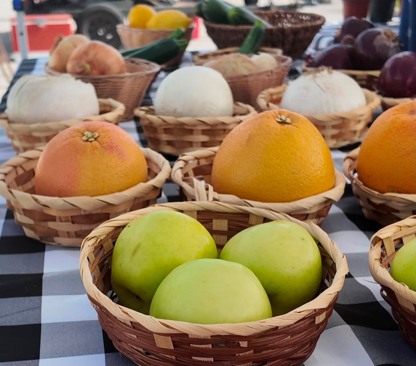 Baskets of grapefruit, green apples, onions and zucchini on a checkered tablecloth