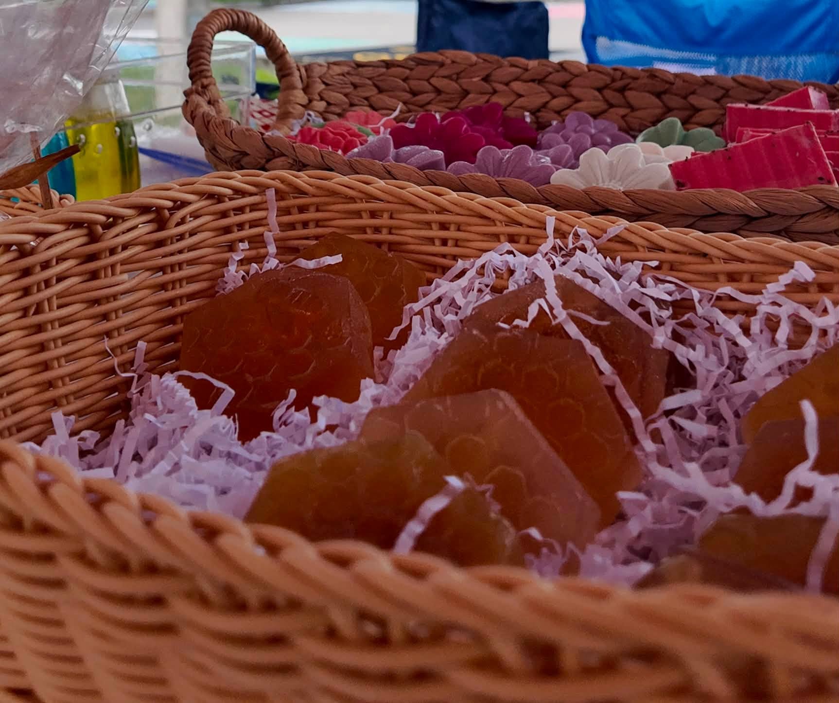 Baskets of honeycomb-shaped soaps and flower-molded bars nestled in paper shred