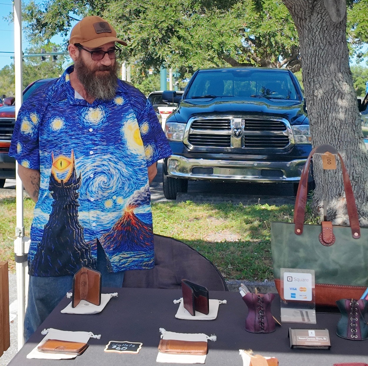 The Smart Custom Worx leather maker behind his table of hand-stitched wallets and a leather tote