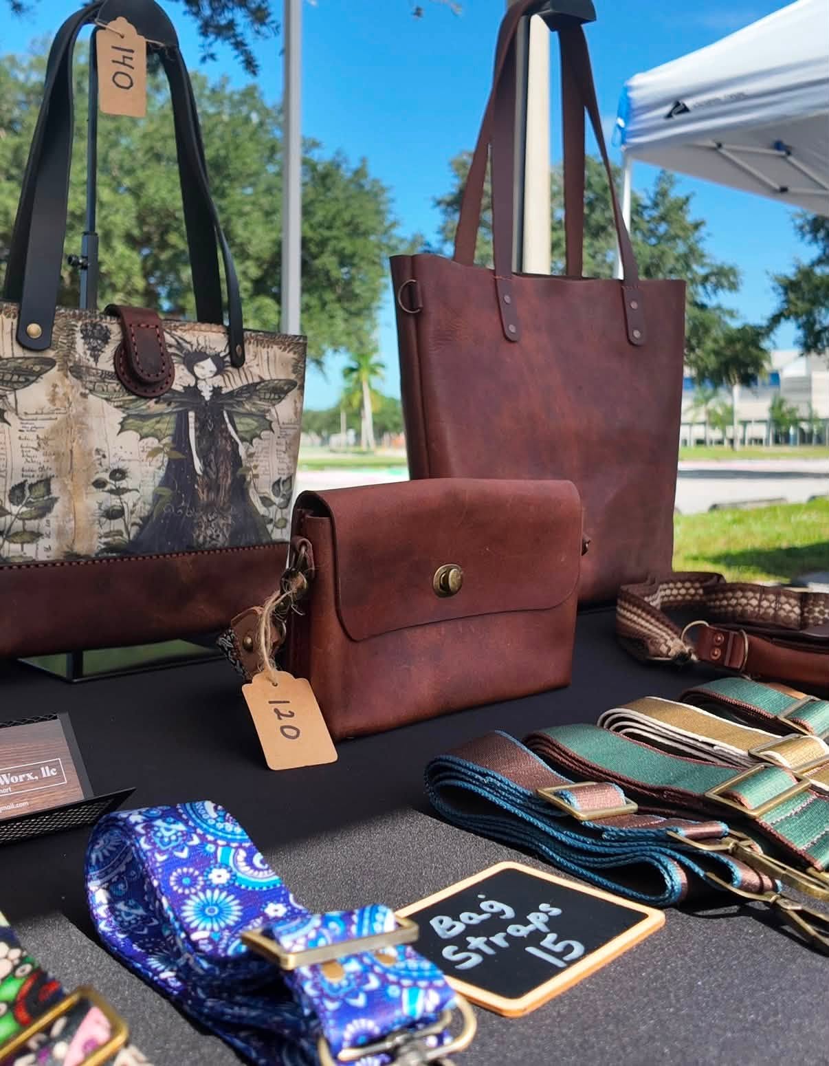 Handmade leather totes and crossbody bags with woven straps on a market table