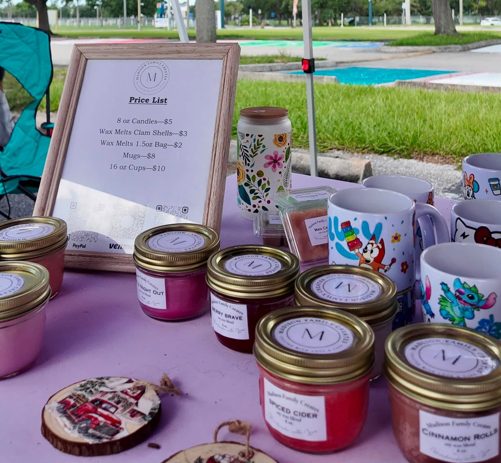 Small-batch soy candles and painted mugs arranged beside a handwritten price list