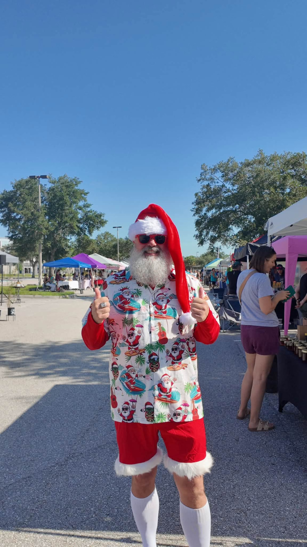 A beach Santa in a Hawaiian shirt giving two thumbs up in the market aisle
